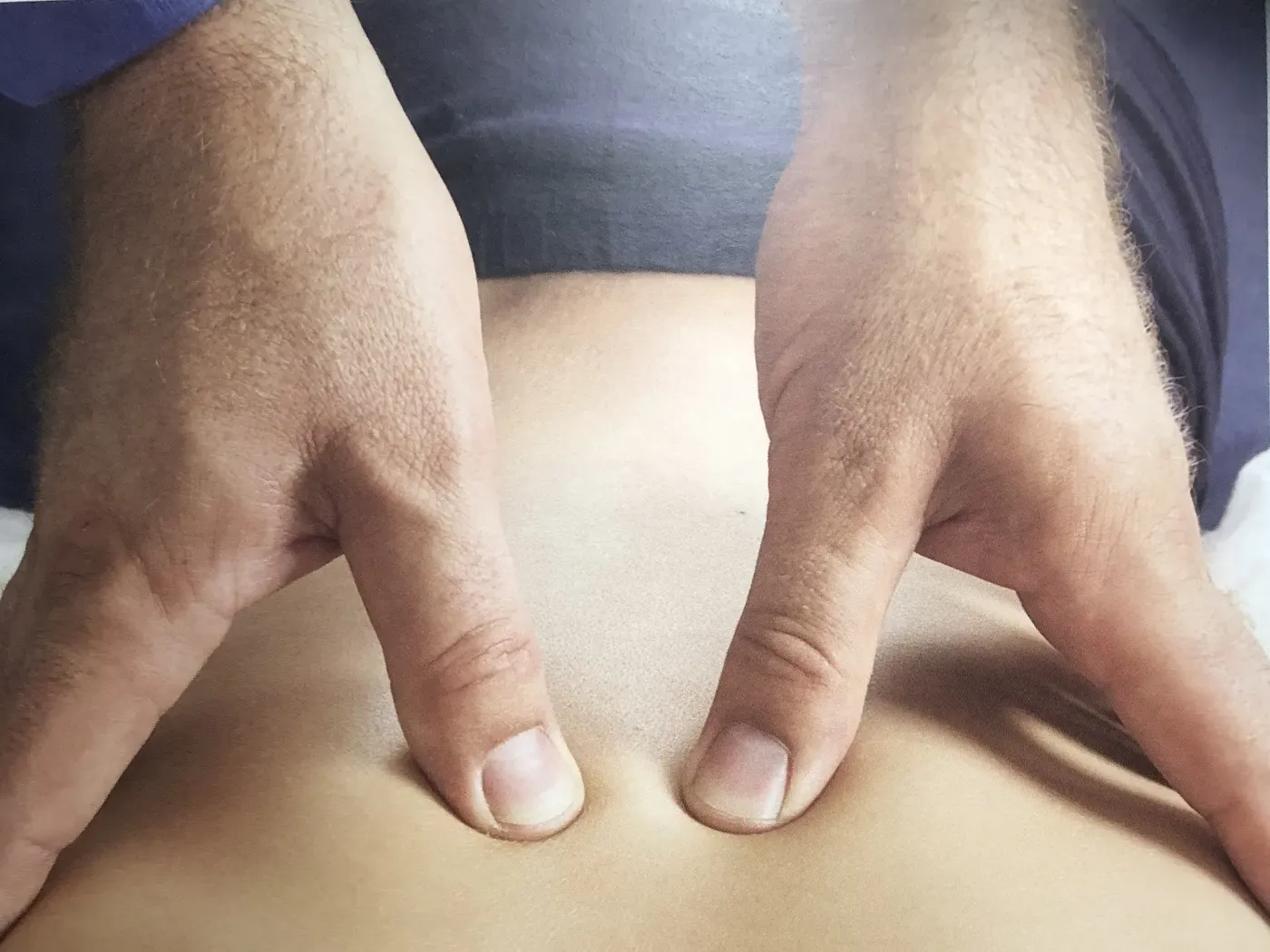 A chiropractor's hands applying pressure either side of a patient's spine